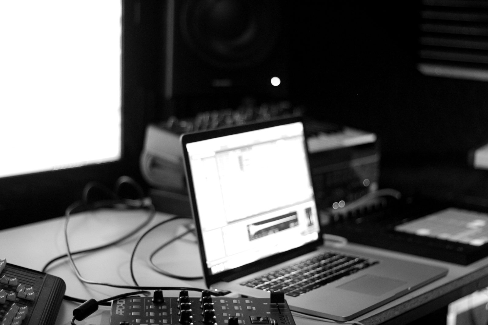 A laptop running Ableton Live on a studio desk with controllers