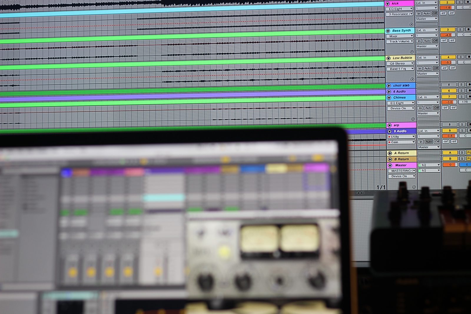 Ableton Live open on a laptop in a studio, with a mixer and controllers around it