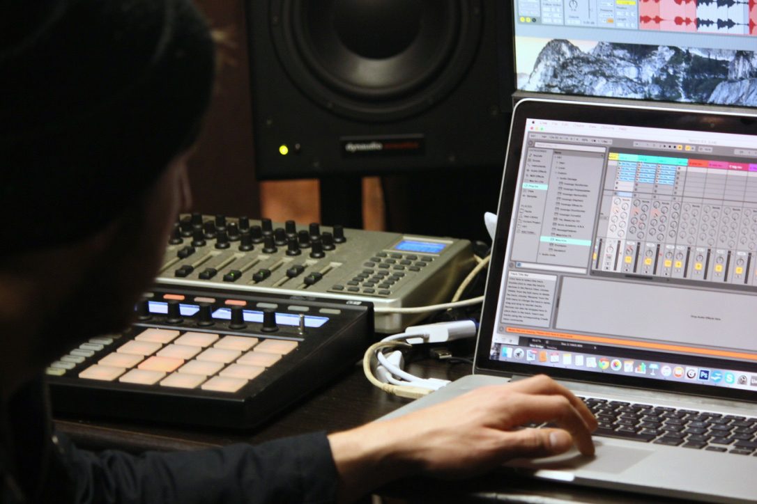 A producer working on a track in Ableton Live with a drum pad controller